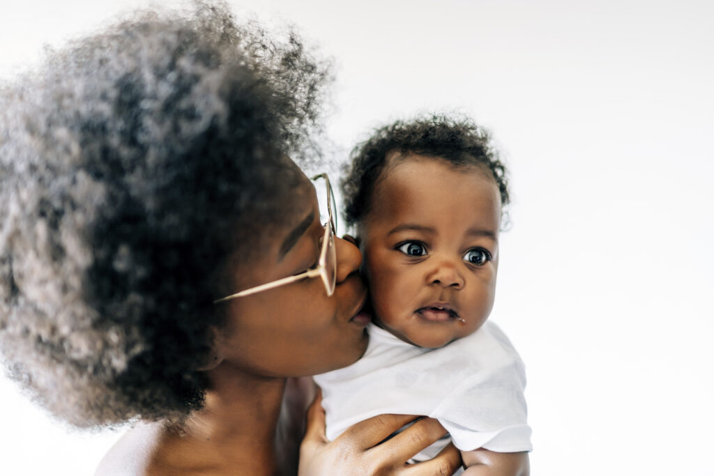 african american mother taking care and loving her baby against a white background