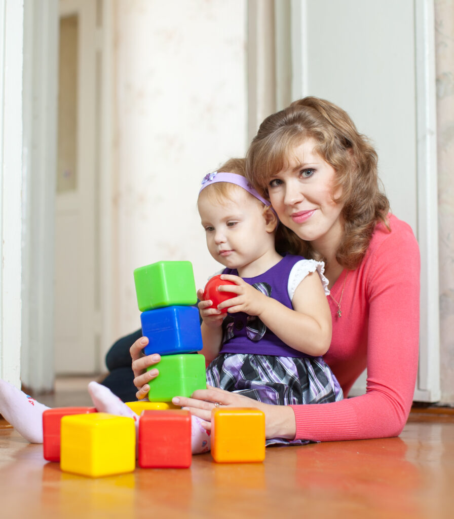 mother and baby girl plays with blocks in home